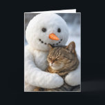 Christmas Snowman Hugging a Tabby Cat Card<br><div class="desc">A snowman with a carrot nose holds a contented tabby cat against a snowy backdrop,  where the cat has its eyes closed,  seemingly enjoying the embrace.
The inside text can be changed.</div>