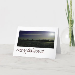 City silhouette on frozen coastline holiday card