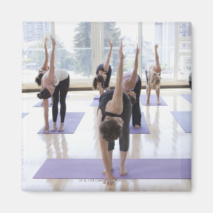 class practicing yoga with instructor in a magnet