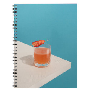 Clear drinking glass with brown liquid notebook