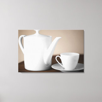 Close-up of a cup and a saucer with a tea kettle canvas print