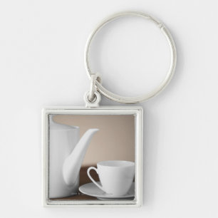 Close-up of a cup and a saucer with a tea kettle key ring