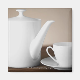 Close-up of a cup and a saucer with a tea kettle magnet
