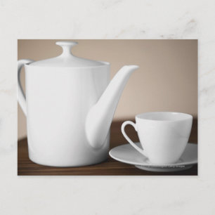Close-up of a cup and a saucer with a tea kettle postcard