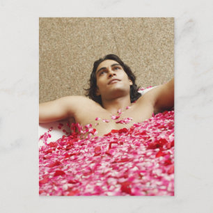 Close-up of a young man lying in a bathtub postcard