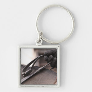 close-up of hand holding reins of horse key ring