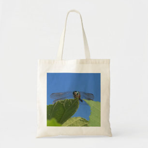 Closeup of a dragonfly against a bright blue sky tote bag