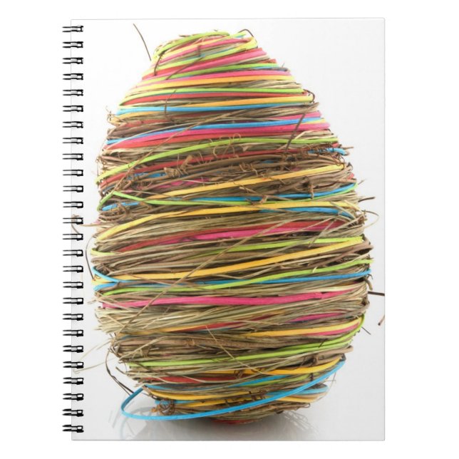 Coloured Straw Easter Eggs Over White Notebook (Front)
