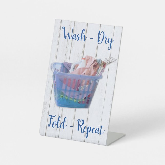 Colourful Folded Laundry On Hangers In Blue Basket Pedestal Sign (Front)