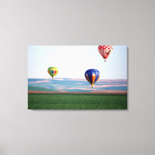 Colourful hot air balloons float over wheat canvas print
