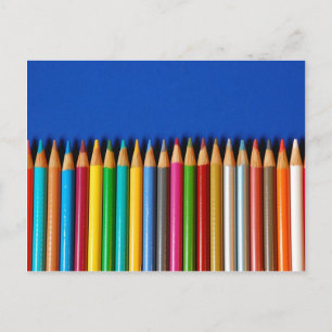 Colourful pencil crayons on blue background postcard