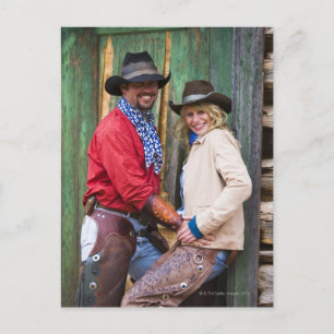 Cowboy and cowgirl holding hands in front of an postcard