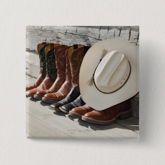 Cowboy hat on row of cowboy boots outside a log 15 cm square badge (Front)