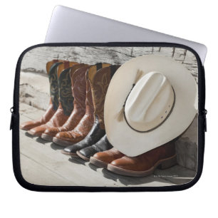 Cowboy hat on row of cowboy boots outside a log laptop sleeve
