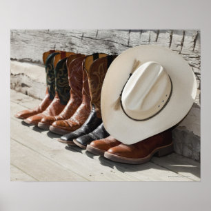 Cowboy hat on row of cowboy boots outside a log poster