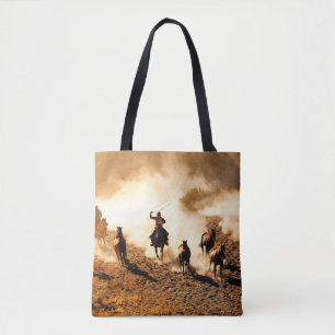 Cowboys chasing wilding horses. roping and riding, tote bag