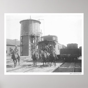 Cowboys on horses posing in front of a train poster