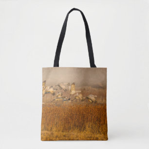 Cranes over a golden field tote bag