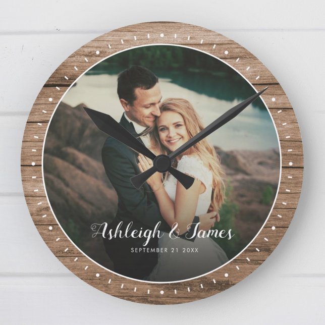 Custom Rustic Modern Wedding Photo Script Round Clock (Rustic wooden clock with a photo of a couple embracing, set against a scenic outdoor backdrop.)