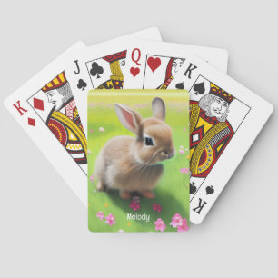 Cute baby rabbit in a flower meadow playing cards