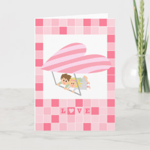 Cute couple flying on a heart-shaped hang-glider holiday card