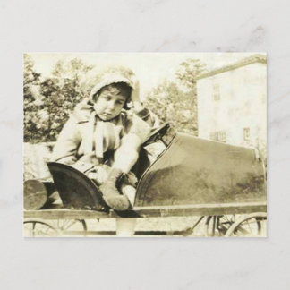 Cute girl in a peddle car postcard