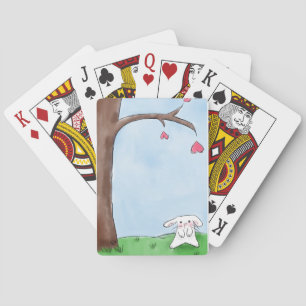Cute white bunny sitting by a tree playing cards