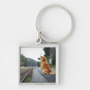 Dog sitting on train station key ring