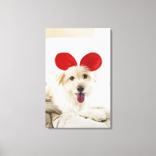 Dog wearing toy ears on bed canvas print