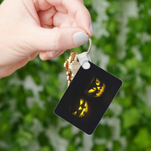 Eerie yellow glow pumpkin faces on black key ring