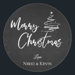 Elegant Chalkboard Script Merry Christmas Tree Classic Round Sticker<br><div class="desc">Elegant Chalkboard Script Merry Christmas Tree Classic Round Sticker. Customise it by changing the names  . The design has Merry Christmas written in pretty font on a chalkboard background along with the names of the couple.  For any further customisation ,  feel free to contact me at mypaperlove2021@gmail.com</div>