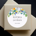 Elegant floral yellow white blue wedding monogram  classic round sticker<br><div class="desc">A radiant colourful wedding stickers with beautiful watercolor green botanical foliage and eucalyptus leaves and sunny elegant yellow white flowers. Add a refined touch to your wedding stationery with this elegant floral yellow, white, and blue monogram classic round sticker. Featuring a sophisticated design with delicate yellow blooms, soft white florals,...</div>
