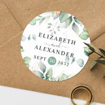 Elegant greenery eucalyptus names and wedding date classic round sticker<br><div class="desc">This romantic and elegant floral wedding round sticker makes the perfect seal for your wedding favour, presenting a chic botanical design that features a classy bouquet of light and airy watercolor greenery and eucalyptus leaves complemented with glittery golden speckles (printed) and is easily customisable with your names and wedding date....</div>