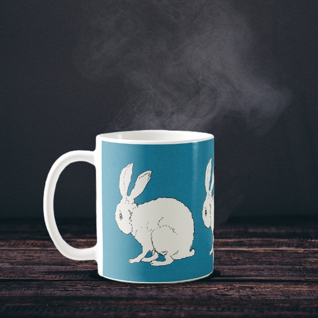 elegant white sitting bunny rabbits on blue  coffee mug (Simple white sitting rabbits on dark blue circling a coffee or tea mug.)