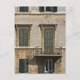 facade of building with a balcony and shuttered postcard