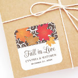 Fall in Love Maple Leaf Wedding Square Sticker<br><div class="desc">Add a sweet seasonal accent to wedding favors and envelopes with this square "Fall in Love" sticker featuring vibrant red, orange, and gold maple leaves over brown scrollwork. The design includes editable couple names and wedding date below the romantic autumn banner. A charming finishing detail for gift bags, favor boxes,...</div>