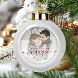 First Christmas Engaged Photo Burgundy Script Ceramic Ball Christmas Ornament<br><div class="desc">Commemorate your engagement with this beautiful modern keepsake ornament. The burgundy red text reads "Our first Christmas engaged, " with the word "engaged" in elegant handwriting script with flourishes before and after. Replace the sample image with your favourite photo, and add your names and the year. A white gradient filter...</div>