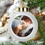 First Christmas Engaged Photo White Modern Ceramic Ball Christmas Ornament<br><div class="desc">Commemorate your engagement with this beautiful modern keepsake ornament. The white text reads "Our first Christmas engaged, " with the word "engaged" in elegant calligraphy script with decorative swashes before and after. Replace the sample image with your favourite photo, and add your names and the year. A dark gradient filter...</div>