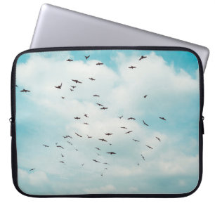 Flock of grey dove fly on vintage blue sky. above, laptop sleeve