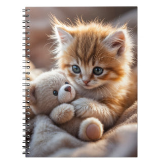 Fluffy red kitten playing with a tiny teddy bear,  notebook