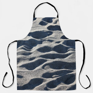 Foot prints on sand during daytime apron