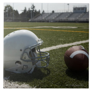 Football and football helmet on football field tile