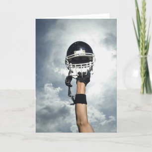 Football player holding helmet in air card
