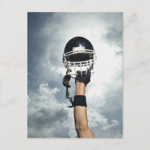 Football player holding helmet in air postcard