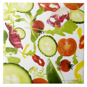 Fresh mixed salad vegetables falling to camera tile