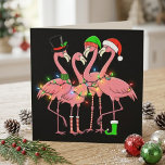 Funny Christmas Flamingos in Santa Hats and Lights Holiday Postcard<br><div class="desc">Funny Christmas Flamingos in Santa Hats and Lights features three pink flamingos dressed for the holidays with Santa hats, a top hat, striped socks, a green boot, and colourful string lights. The black background makes the bright festive details stand out and gives the artwork a bold seasonal look. This playful...</div>