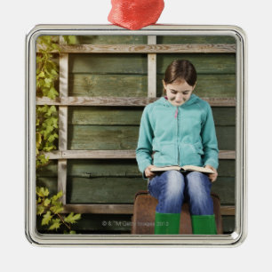 Girl sitting and reading book near vine metal tree decoration