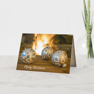 gold Christmas ornaments by fireplace Holiday Card