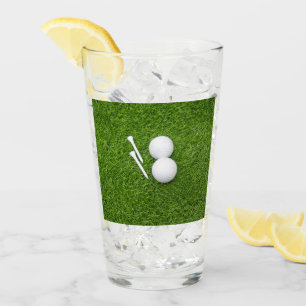 Golf ball and tee are on green grass glass