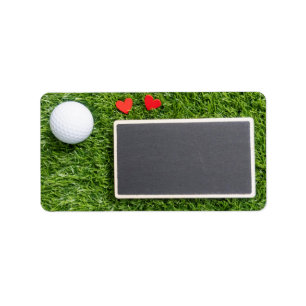 Golf ball with two hearts are on green with board label